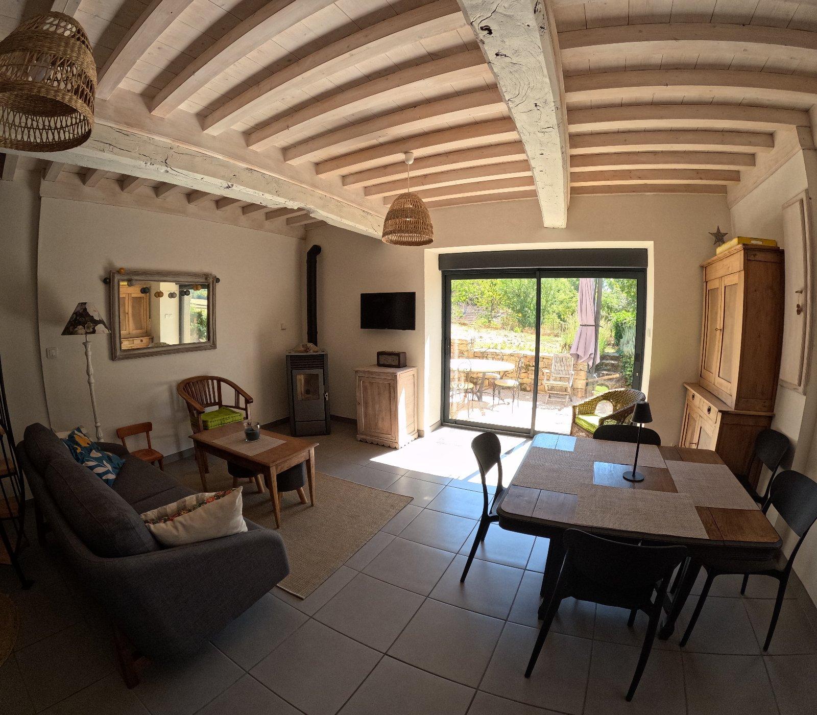 Le séjour, la table et la baie vitrée ouverte sur la terrasse