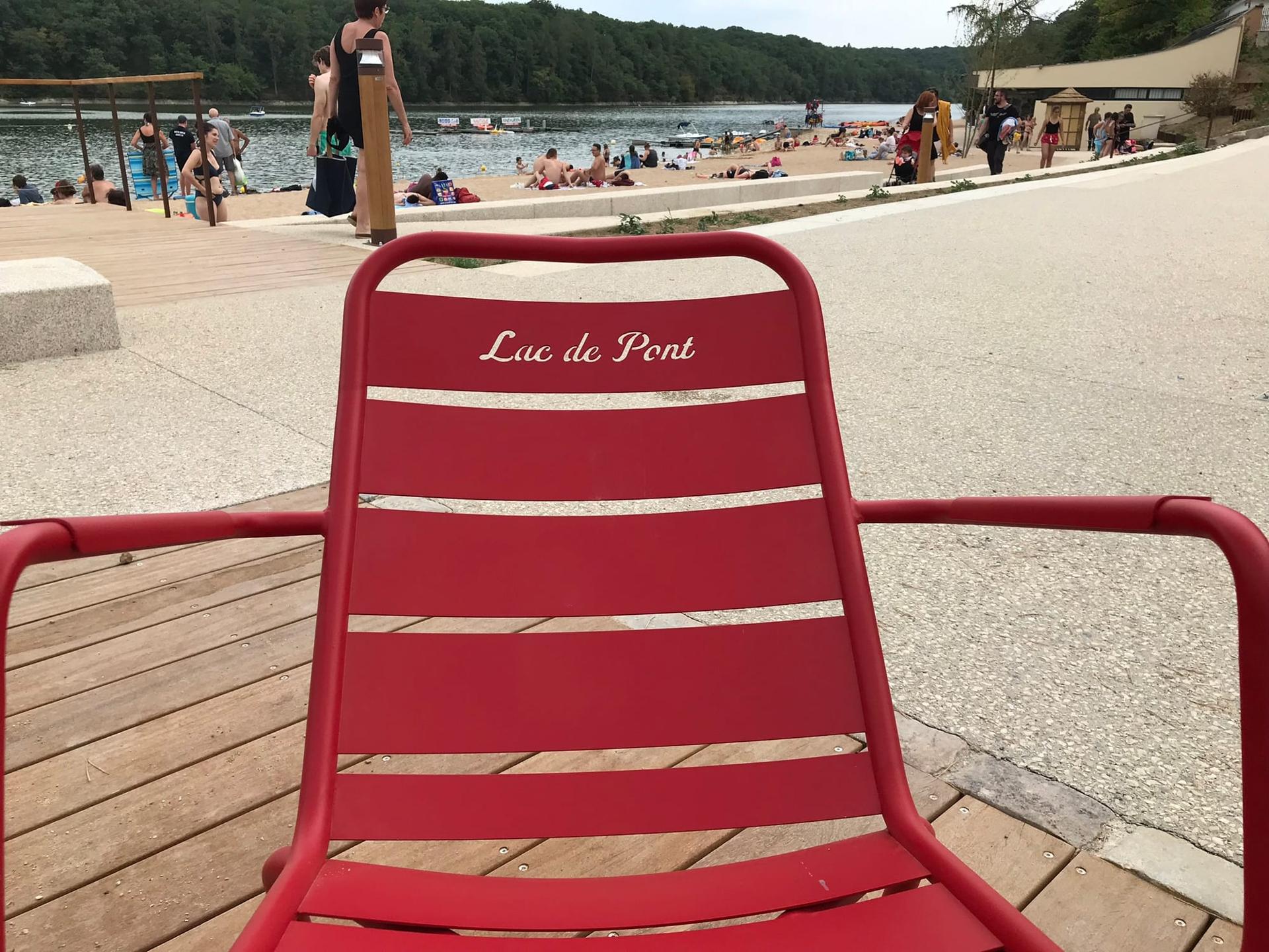 Une chaise rouge marquée « Lac de Pont », face à la plage